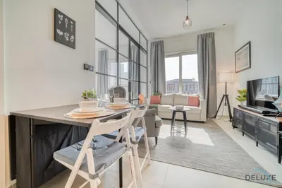 a kitchen and living room with a table and chairs at Jovial 1BR at Collective Tower 2 Mohammed Bin Rashid City by Deluxe Holiday Homes in Dubai