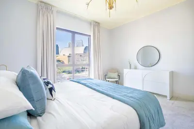 a white bedroom with a large window and a bed at GuestReady - Sweet Sunshine in Downtown in Dubai