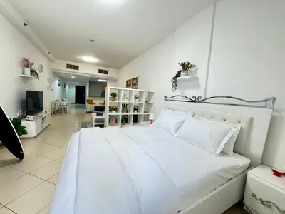 a white bedroom with a white bed and a living room at Spacious studio apartment in Dubai Marina close to metro and beach in Dubai