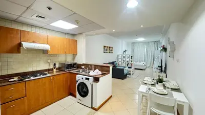 a kitchen with a washing machine and a dining room at Spacious studio apartment in Dubai Marina close to metro and beach in Dubai