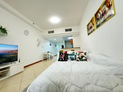 a bedroom with a large white bed and a flat screen tv at Spacious studio apartment in Dubai Marina close to metro and beach in Dubai