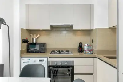 a kitchen with white cabinets and a stove top oven at Cozy 1bdr 10' from Burj Khalifa in Dubai
