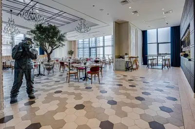 a man standing in a large room with tables and chairs at Luxury 3 bedroom apartment in Paramount Midtown in Dubai