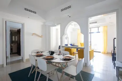 a white dining room with a table and chairs at Chic 2BR with Burj Khalifa View in Souk Al Bahar in Dubai