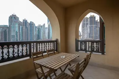 a table and chairs on a balcony with a view of a city at Chic 2BR with Burj Khalifa View in Souk Al Bahar in Dubai