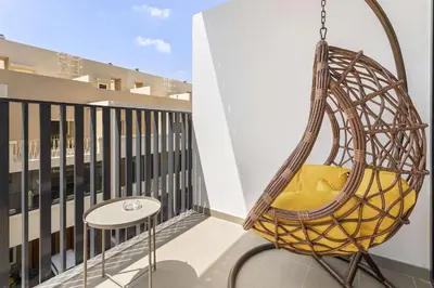 a hanging chair on a balcony with a table at Silkhaus Modern Studio In a Quiet Neighborhood in Dubai