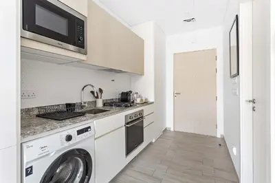 a kitchen with a washing machine and a microwave at Silkhaus Modern Studio In a Quiet Neighborhood in Dubai