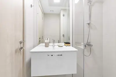 a white bathroom with a sink and a shower at Silkhaus cozy studio in JVC Luma21 in Dubai