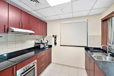 a kitchen with red cabinets and a white wall at StoneTree - Time Place Tower 1 BR - Amazing View in Dubai