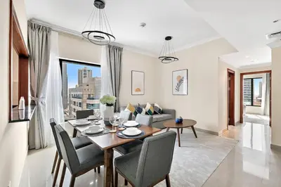 a dining room and living room with a table and chairs at StoneTree - Time Place Tower 1 BR - Amazing View in Dubai
