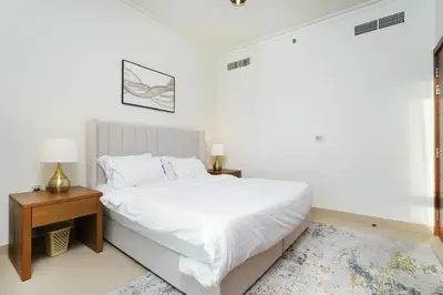 a white bedroom with a white bed and a night stand at AMAKIN Burj Vista Tower 1 in Dubai