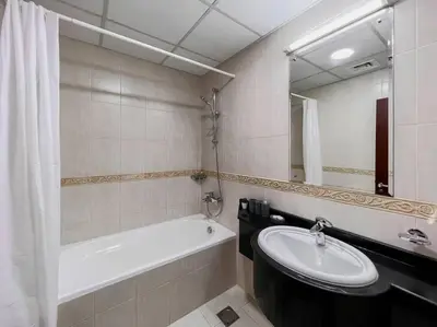 a bathroom with a sink and a bath tub and a mirror at StoneTree - Elite Residence 1 BR - Near Dubai Tram in Dubai