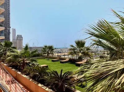 a park with benches and palm trees in a city at StoneTree - Elite Residence 1 BR - Near Dubai Tram in Dubai