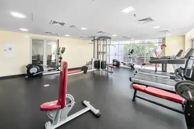 a man in a gym with several tread machines at StoneTree - SkyView Tower 1 BR - Best Location in Dubai