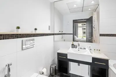 a white bathroom with a sink and a mirror at StoneTree - SkyView Tower 1 BR - Best Location in Dubai