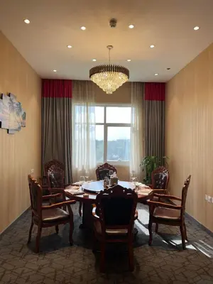a dining room with a table and chairs and a chandelier at Peony Hotel in Dubai