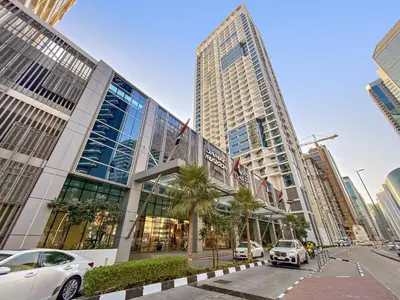a large building with cars parked in front of it at ALiving Elegant Studio with Balcony I Canal View I DAMAC Maison Prive- 706B in Dubai