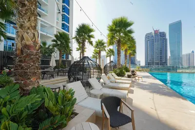 a pool at a hotel with white chairs and palm trees at ALiving Elegant Studio with Balcony I Canal View I DAMAC Maison Prive- 706B in Dubai