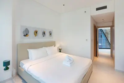 a white bedroom with a white bed and a window at Marquise Square - 2Br Apartment - Allsopp&Allsopp in Dubai