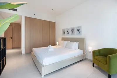 a bedroom with a white bed and a green chair at Marquise Square - 2Br Apartment - Allsopp&Allsopp in Dubai