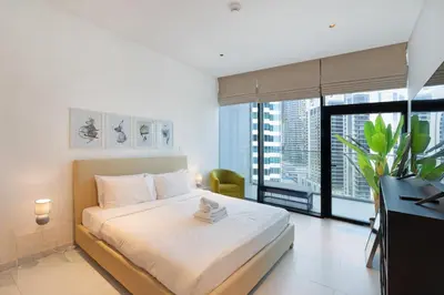 a bedroom with a bed with a desk and a large window at Marquise Square - 2Br Apartment - Allsopp&Allsopp in Dubai