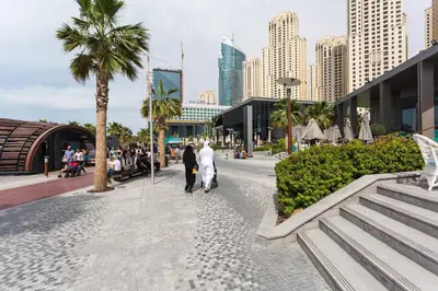 a couple of people walking down a street in a city at JBR Beach - Panoramic Sea View 2BR Apartment in Dubai