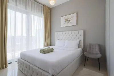a white bedroom with a large bed and a chair at Business Bay 1 bedroom with Canal view in Dubai