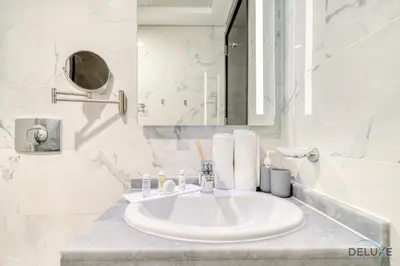 a white bathroom with a sink and a mirror at Classic 1BR at MAG 510 Dubai South by Deluxe Holiday Homes in Dubai