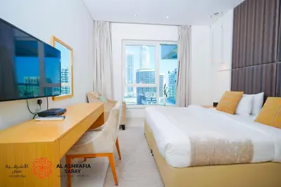 a hotel room with a bed and a desk and a tv at Alashrafia Saray - Spectacular 2BR in Canal Views in Dubai
