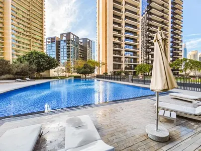 a swimming pool with an umbrella and chairs and buildings at Charming 2Br in Boulevard Crescent - Downtown Dubai in Dubai