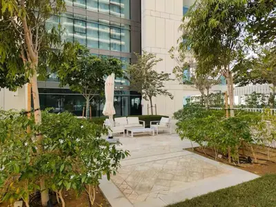 a courtyard with white furniture and trees in front of a building at Vogue Emaar Beachfront Beach Vista near JBR and Palm Jumeirah, One Bedroom Apartment with Balcony and Private Beach, Access to all Amenities in Dubai