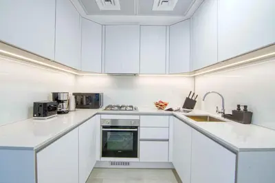 a white kitchen with white cabinets and appliances at The Smart Concierge - Luma 21 in Dubai
