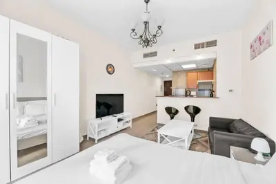 a living room with a table and a couch and a tv at StoneTree - Marina Diamond Studio - Near Metro Station in Dubai
