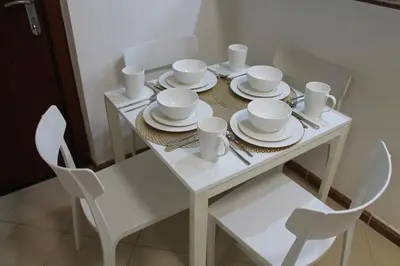 a white table with white plates and dishes on it at Newly furnished cozy 1 bedroom apartment close to JBR beach and metro in Dubai