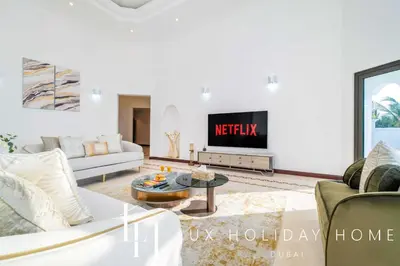 a living room with a couch and a tv at LUX The Ultimate Island Palm Villa in Dubai