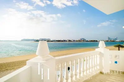 a view of the beach from the balcony of a white building at LUX The Ultimate Island Palm Villa in Dubai