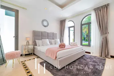 a bedroom with a large bed with a pink blanket at LUX The Ultimate Island Palm Villa in Dubai
