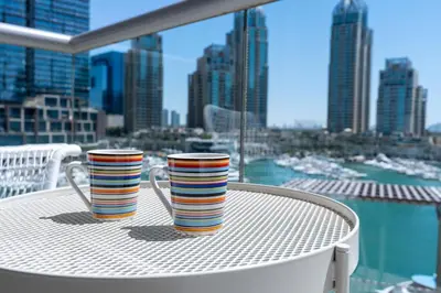 two colorful cups sitting on a table on a balcony at Vacay Lettings- Stylish waterfront getaway home in Dubai
