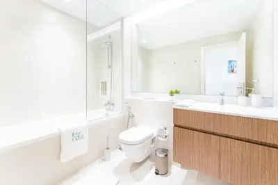 a white bathroom with a toilet and a sink at Stunning 2BR Apartment in Port De La Mer in Dubai