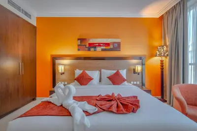 a bedroom with a large white bed with orange walls at Icon Delux Hotel Apartments Al Barsha - Formerly Abidos in Dubai