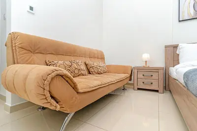 a brown couch in a bedroom with a bed at 1bd apt plus study I Close to mall I Fast wi-fi in Dubai