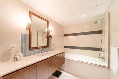 a bathroom with a tub and a sink and a mirror at 2 Bedroom App with private beach and infinity pool in Dubai