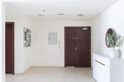 a hallway with two wooden doors and a vase of flowers at High Floor Elegance,Prime Location-Close to tram in Dubai