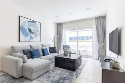 a white living room with a couch and a tv at High Floor Elegance,Prime Location-Close to tram in Dubai