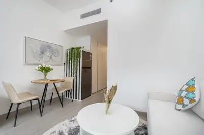 a white living room with a table and chairs at Very Cozy & Relaxing Studio in JVC in Dubai