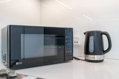 a microwave sitting on a counter next to a coffee pot at Work & Relax & Chill in JVC in Dubai