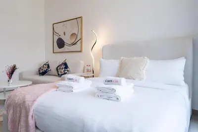 a bedroom with a white bed with towels on it at Work & Relax & Chill in JVC in Dubai