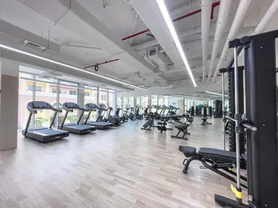 a gym with rows of treadmills and machines at Brand New & Modern Studio in JVC in Dubai