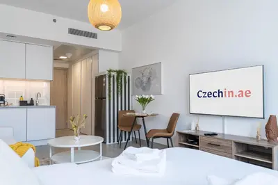 a kitchen and a living room with a table and chairs at Brand New & Modern Studio in JVC in Dubai