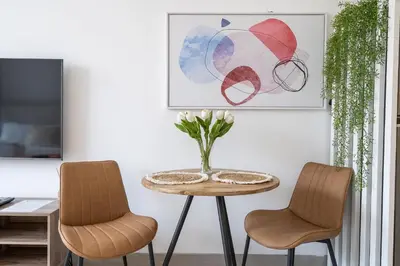 a table with two chairs and a vase with flowers on it at Bright & Modern Studio in JVC in Dubai